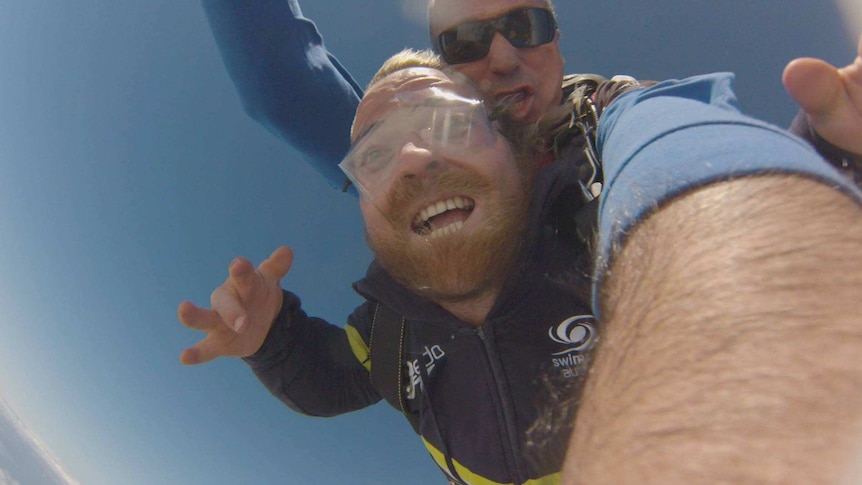 Man with beard skydiving with instructor.