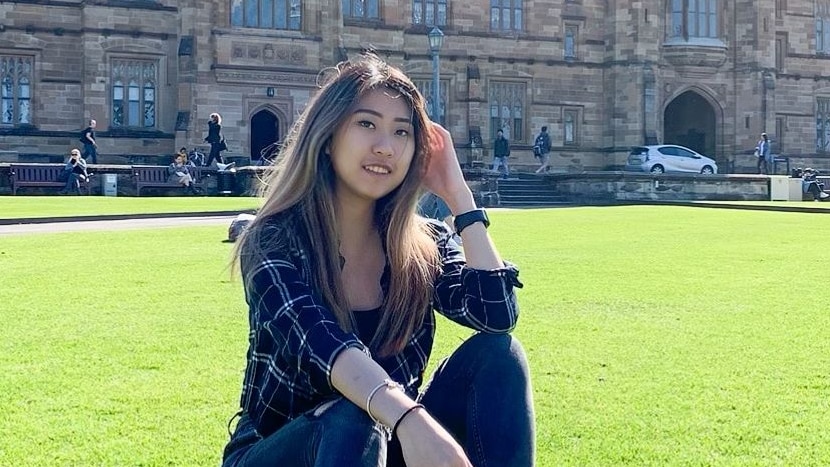 Stella sitting on the grass in front of campus.