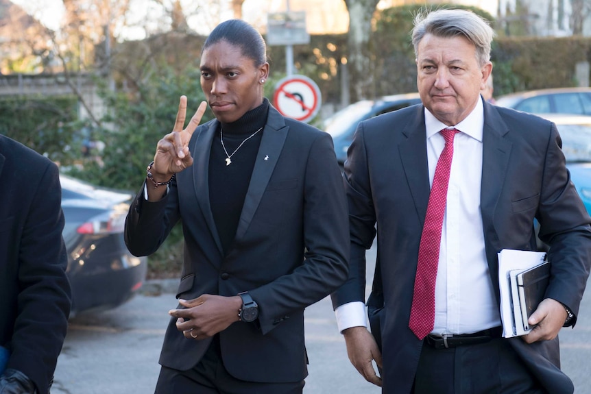 A woman makes the victory sign as she walks with her lawyer.