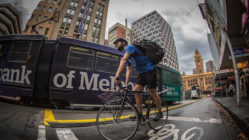 Wide-angle shot from low to the ground looking up at a man with a large backpack on a bicycle