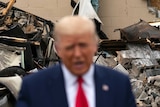 President Donald Trump speaks with damage in the background.