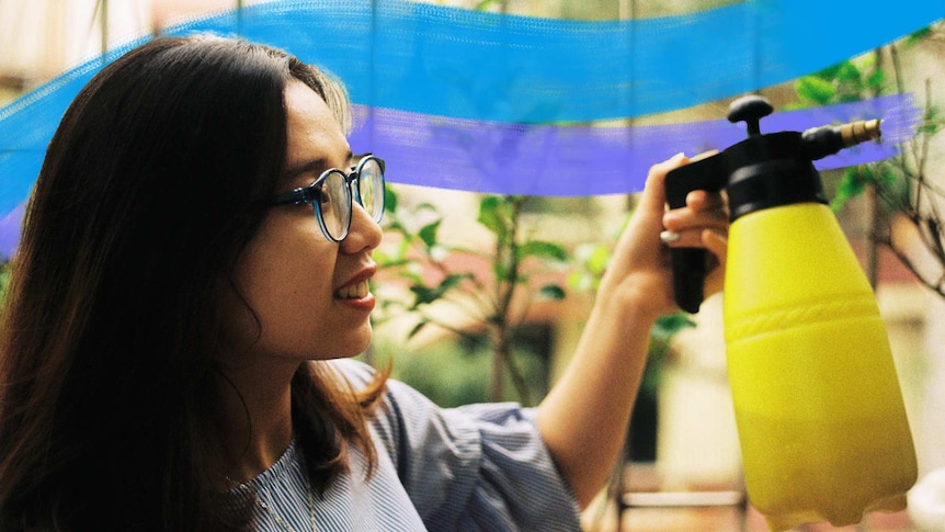 A woman waters her plants with a hand pump, careful not to overwater her indoor plants.