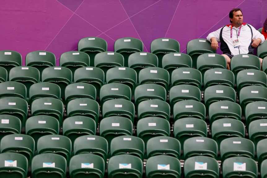 Tennis spectator sits amid empty seats at the 2012 London Olympic Games