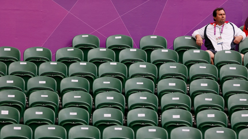 A spectator sits amid empty seats during an Olympic women's singles match.