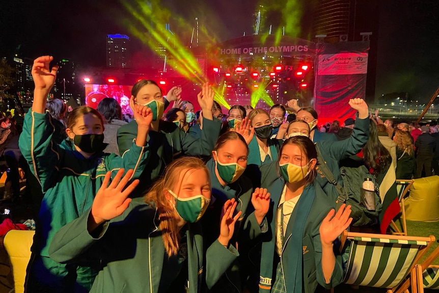 Students in green and gold masks cheering.