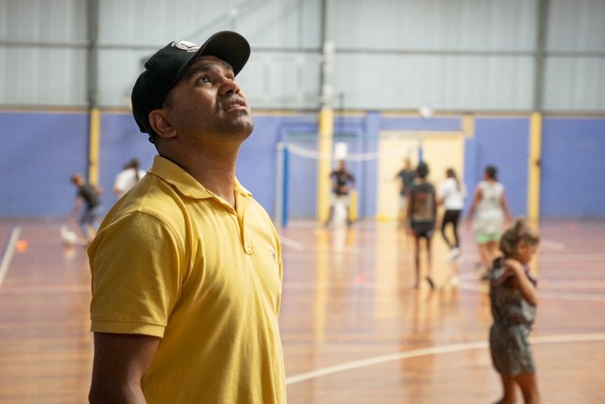 Youth caseworker Lloyd Munro stares to basketball ring above inside the Moree PCYC hall.