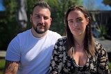 Man and woman sit next to each other facing the camera.