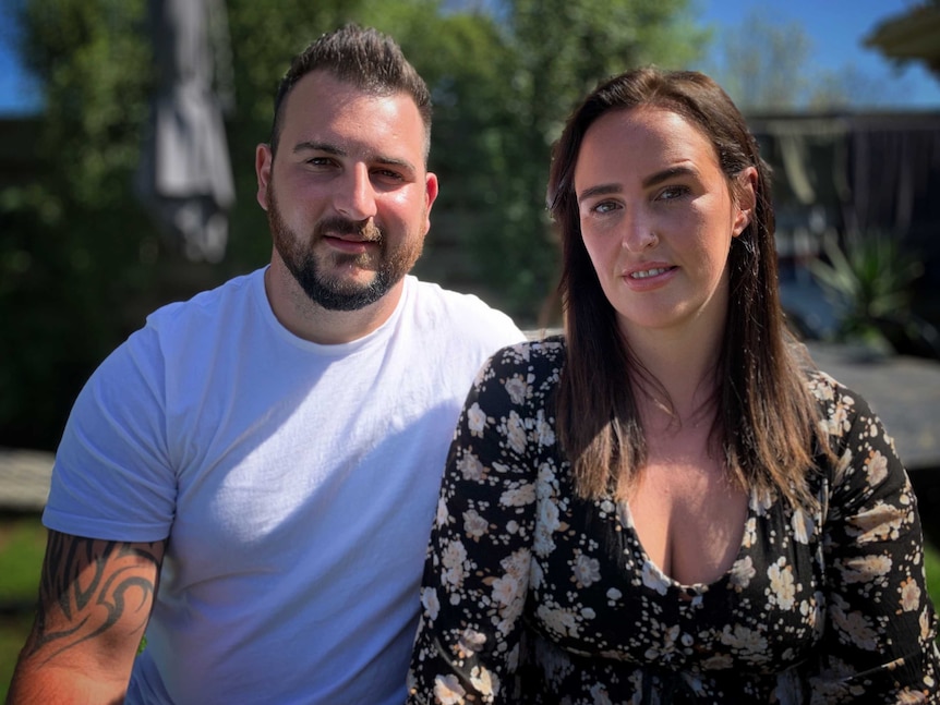 Man and woman sit next to each other facing the camera.