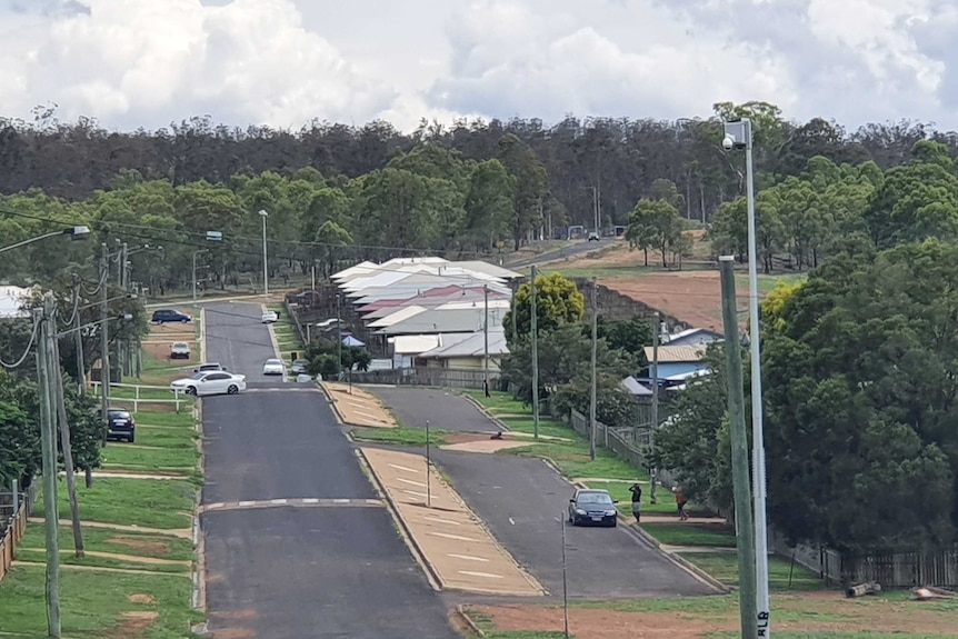 a long street with a group of houses and trees in the distance