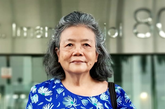 Woman with grey hair standing in front of a building in Jakarta.