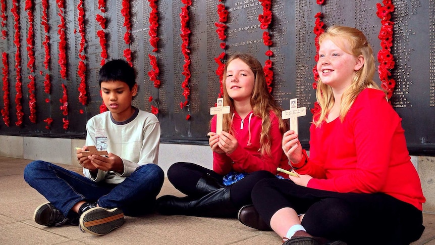 Canberra school students writing on their wooden crosses.