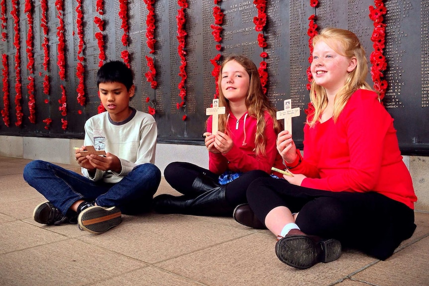 Canberra school students writing on their wooden crosses.