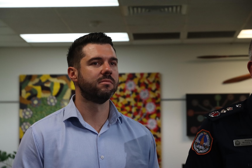 NT Police Minister Brent Potter standing and looking serious, inside an office.