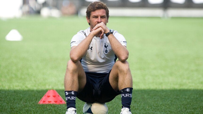 Andre Villas Boas wears soccer kit as he sits on a soccer ball, with hits elbows on knees, hand clasped at his chin