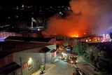 Smoke and flames billowing from industrial buildings at night