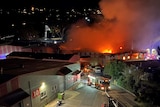 Smoke and flames billowing from industrial buildings at night