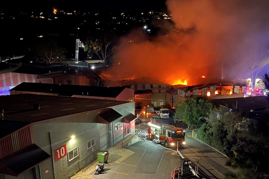 Smoke and flames billowing from industrial buildings at night