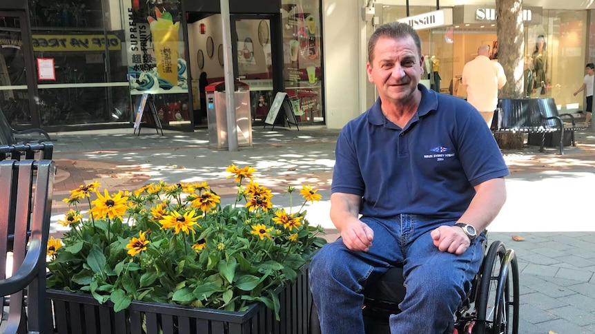 Disability advocate David Cawthorn sitting near some blooming flowers in Elizabeth Mall