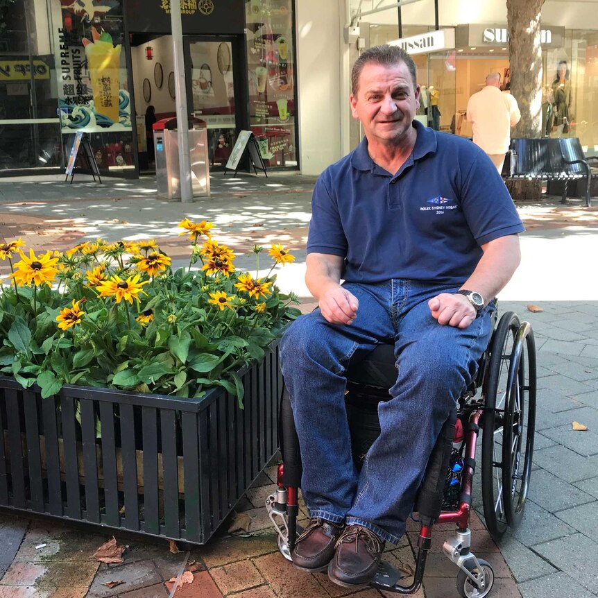 Disability advocate David Cawthorn sitting near some blooming flowers in Elizabeth Mall