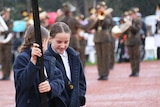 Two girls holding a sign march in the Anzac parade in Canberra in the rain.