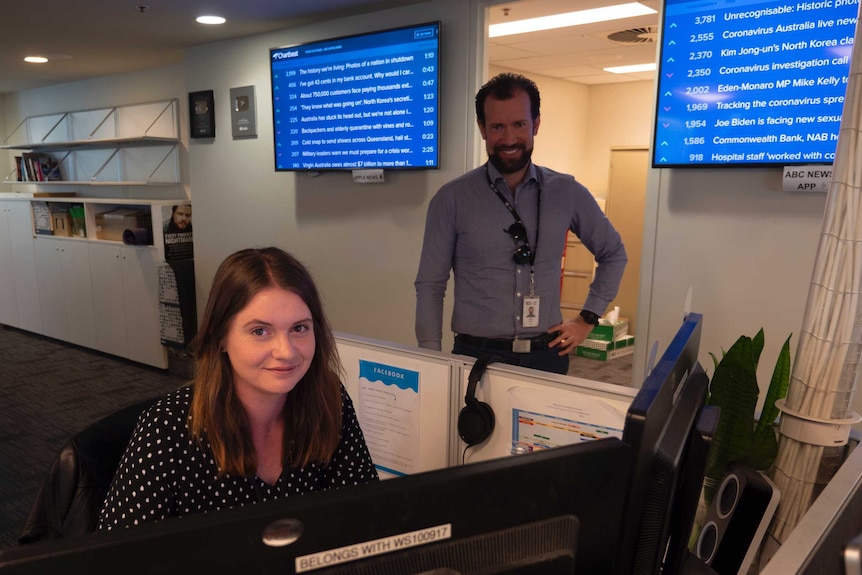 Judd sitting at desk with Smale standing behind her.