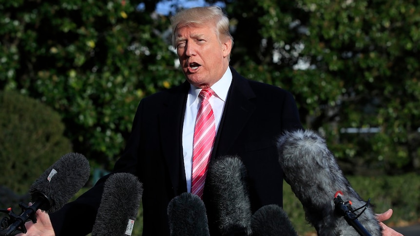 Donald Trump holds his arms out as he speaks to reporters.