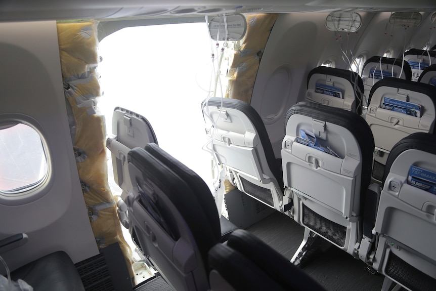 Falta un panel en el lateral de un avión entre dos filas de asientos de pasajeros.