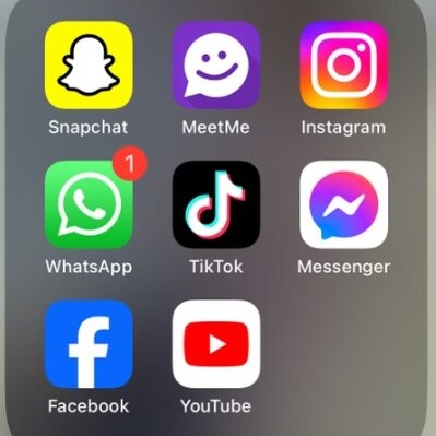 man with straight face in suit and tie and social media app icons on a phone screen