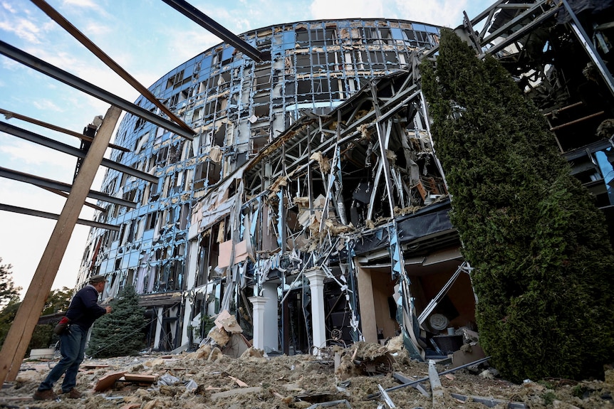 A man stands next to a business and entertainment centre heavily damaged by a Russian military strike