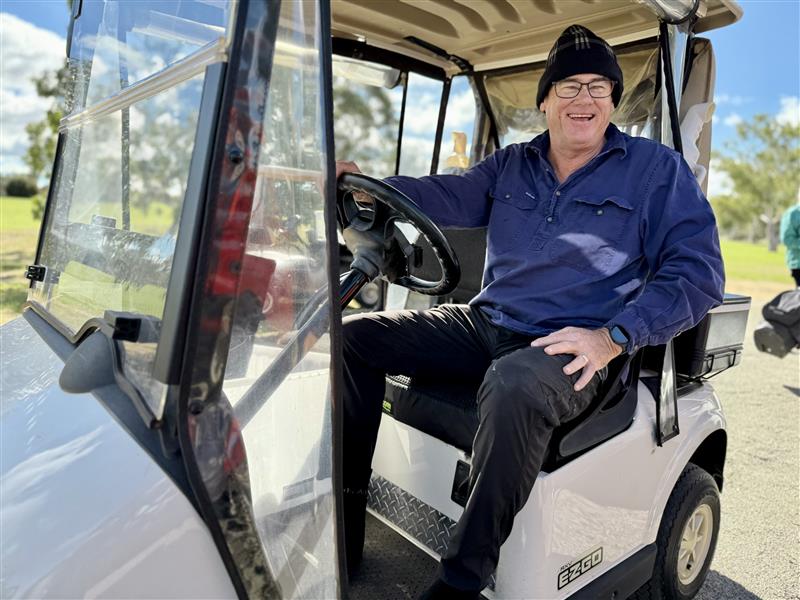 Man in beanie sits inside a golf cart