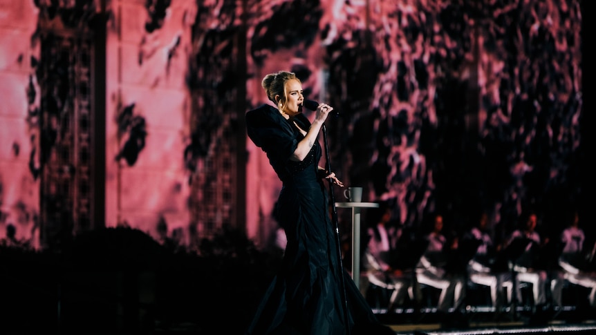 Adele singing on stage wearing a long black dress