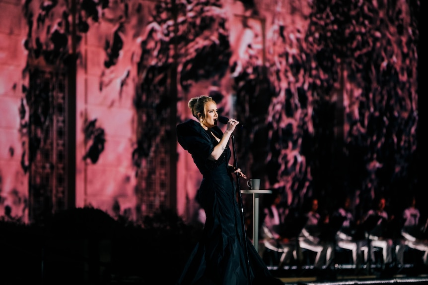 Adele singing on stage wearing a long black dress