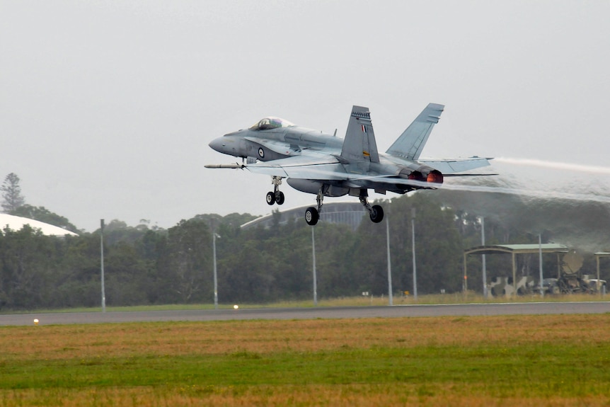 A military plane takes off from an airstrip.