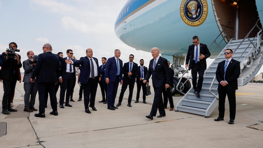 Joe Biden walks away from Air Force One with a number of men in suits surrounding him.