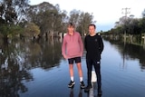 Two teenage boys standing near a flooded road.
