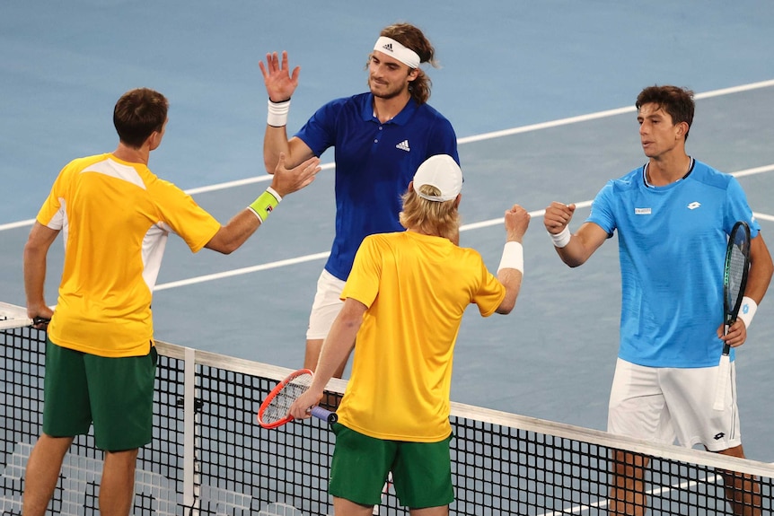 Tennis players congratulate each other at the net.