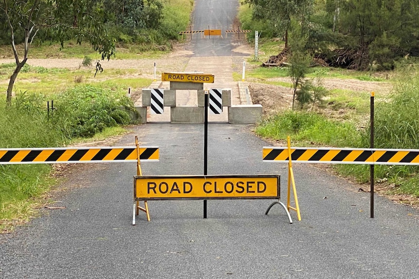 'Road closed' signs and concrete blocks on a rural road.