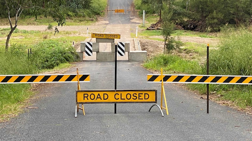 'Road closed' signs and concrete blocks on a rural road.