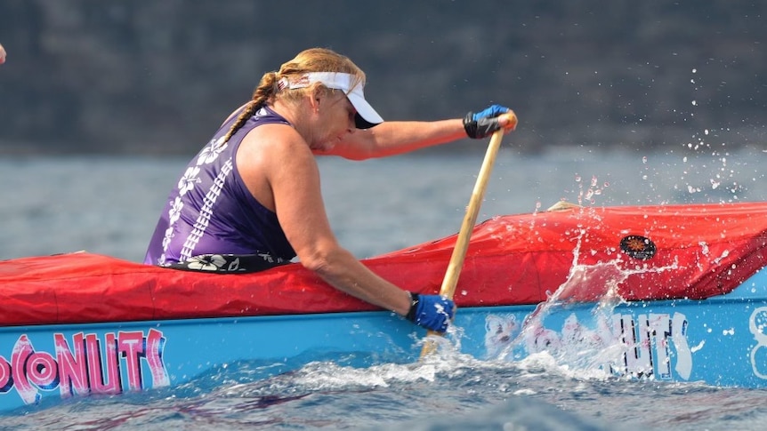 An older woman in action in a canoe