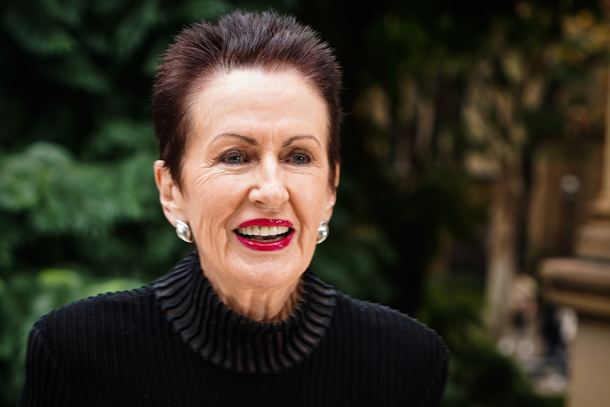 A woman smiles at something beyond the camera.