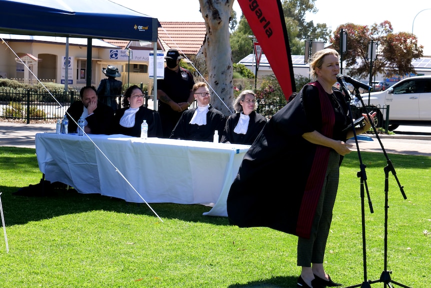 a judge stands to address  a crowd