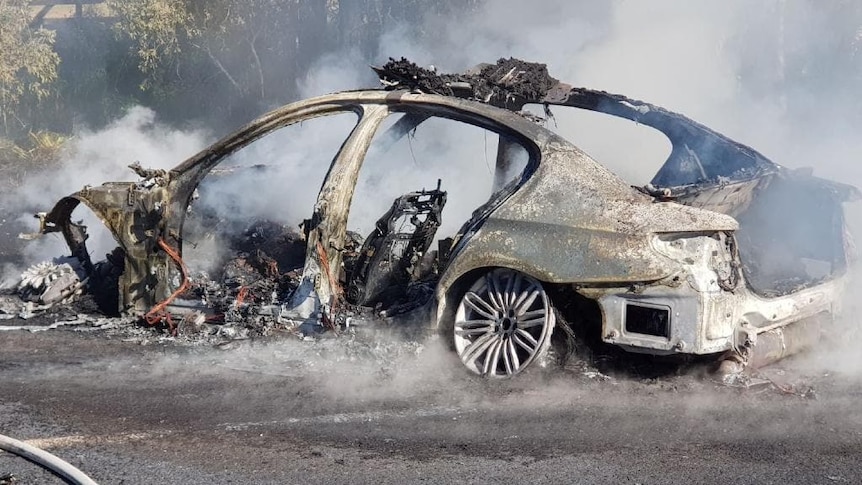 The burnt-out remains of a BMW police highway patrol car on the side of the road