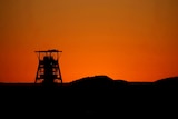 A pit head is seen at the Tumela platinum mine in front of a sunset.