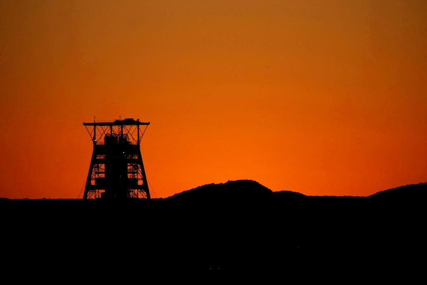 A pit head is seen at the Tumela platinum mine in front of a sunset.