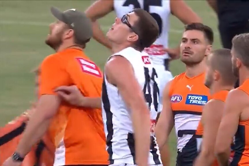 A Channel Seven screenshot of Collingwood Magpies' Mason Cox touching GWS Giants assistant Shane Mumford.