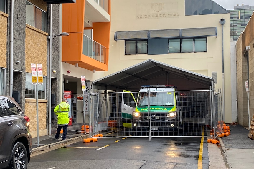 an ambulance surrounded by a temporary fence outside a hotel on a wet street