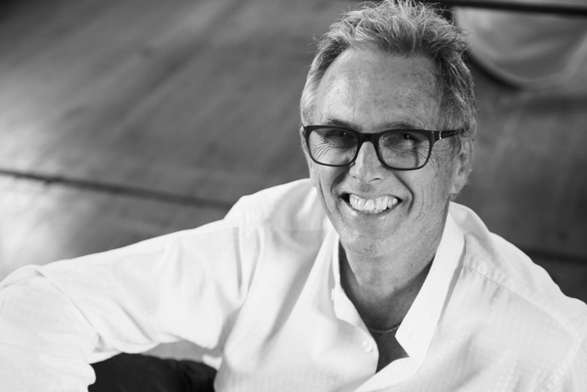 A black and white photo of a middle-aged man wearing glasses and a white shirt.