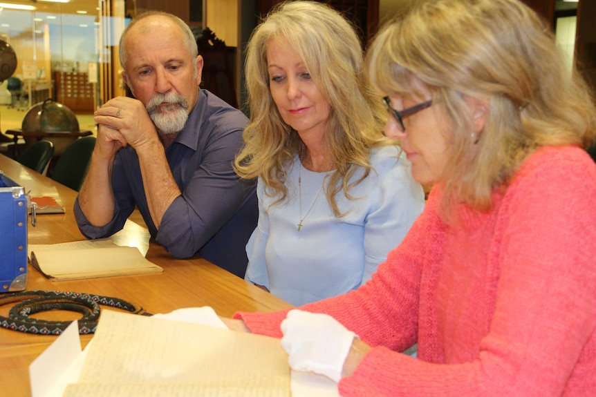 A man and two women examine historical documents.