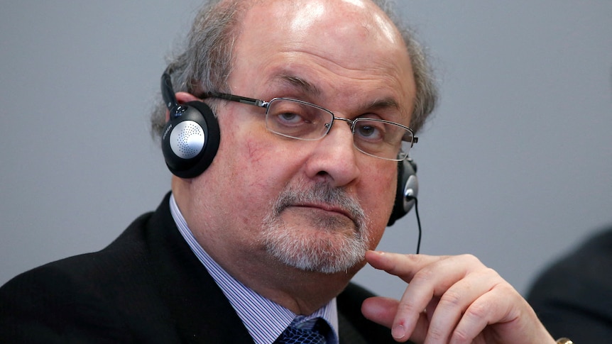 Salman Rushdie with headphones on, listening intently