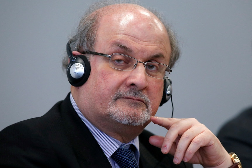 Salman Rushdie nosi słuchawki i uważnie słucha